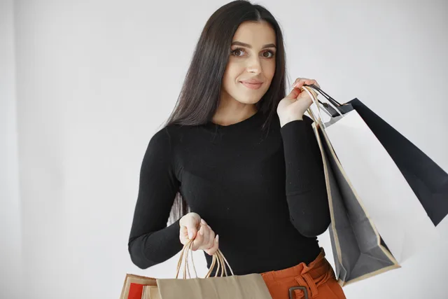 Stylish woman in black shirt holding multiple shopping bags with a white background. A Method for Segmenting Customers by Purchase Rhythm